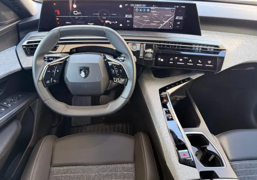 Vue intérieure frontale du poste de conduite du Peugeot 5008 gris Artense 2025, avec tableau de bord numérique et volant compact multifonction.
