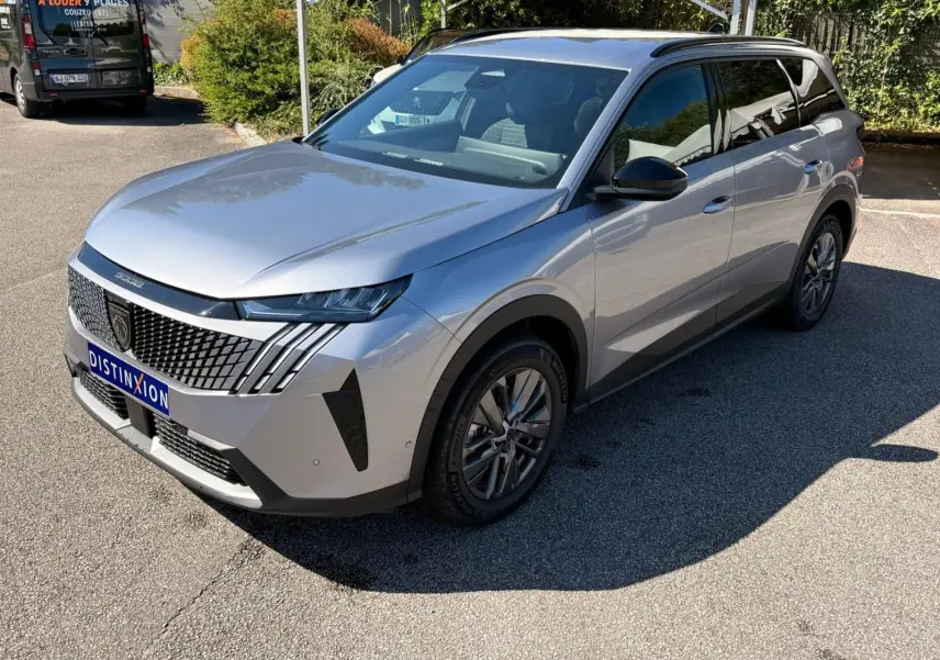 Peugeot 5008 gris Artense en 3/4 avant droit, mettant en valeur sa calandre distinctive et ses phares LED fins.
