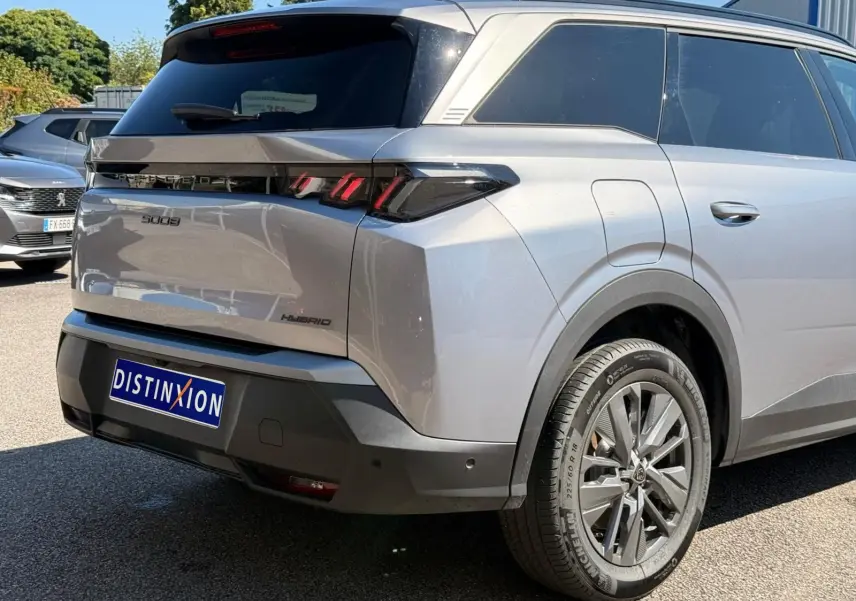 Vue 3/4 arrière droite du Peugeot 5008 gris Artense hybride 2025 avec feux arrière LED et jantes alliage.