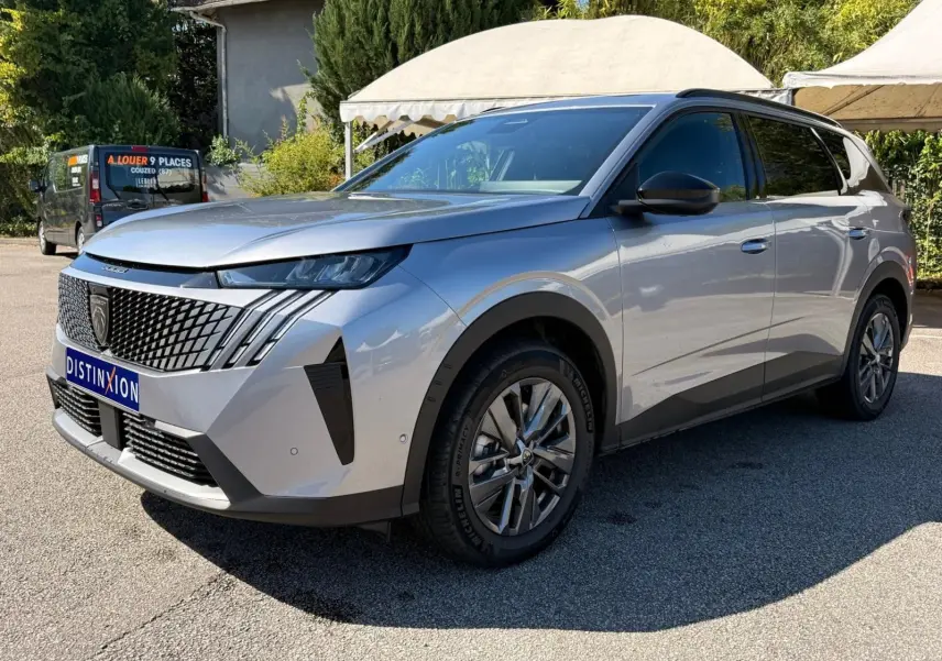 Peugeot 5008 gris Artense en vue 3/4 avant droit, avec calandre distinctive et jantes alliage modernes.