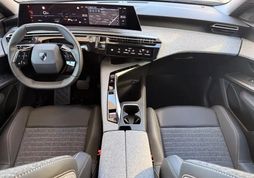 Vue intérieure avant du Peugeot 5008 2025, tableau de bord moderne avec écran digital large et sellerie gris foncé.