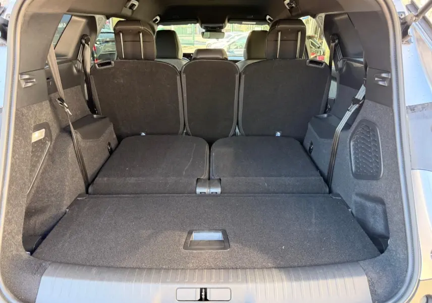 Vue arrière du coffre du Peugeot 5008 gris Artense 2025 avec sièges arrière partiellement rabattus et espace de chargement étendu.