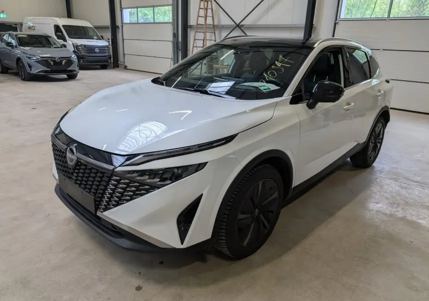 Nissan Qashqai blanc nacré en 3/4 avant droit, avec calandre noire et jantes alliage 19 pouces Aero.