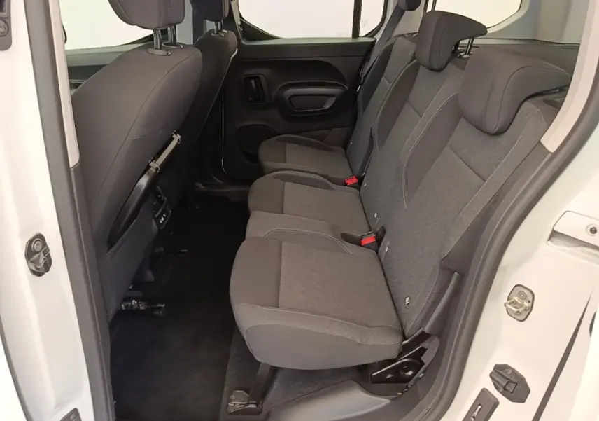 Vue intérieure côté droit sur la banquette arrière grise du Peugeot Rifter blanc, avec porte ouverte.