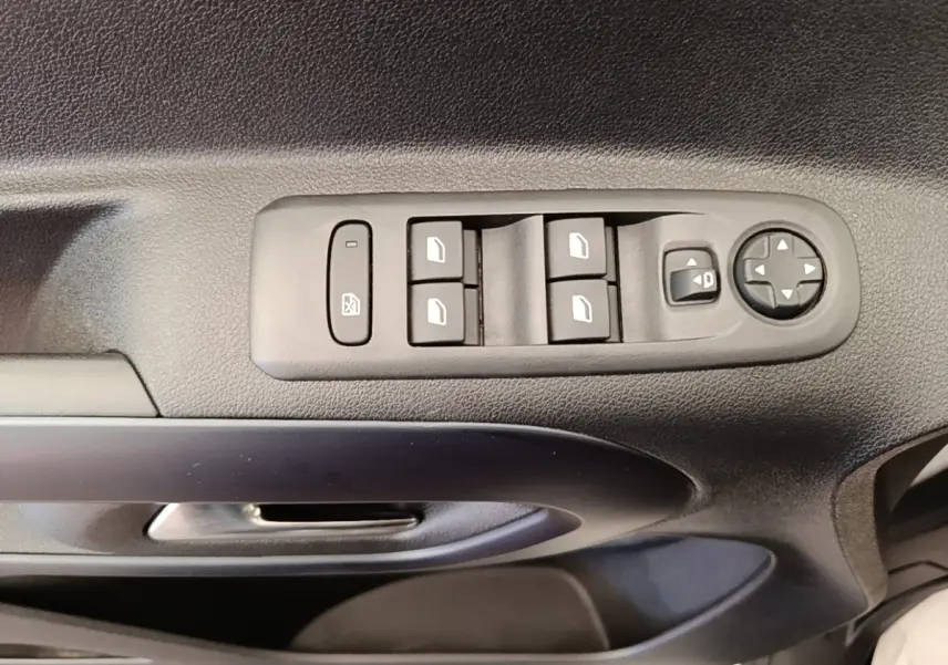 Gros plan sur la commande des vitres électriques et des rétroviseurs sur la porte côté conducteur d’un Peugeot Rifter blanc.