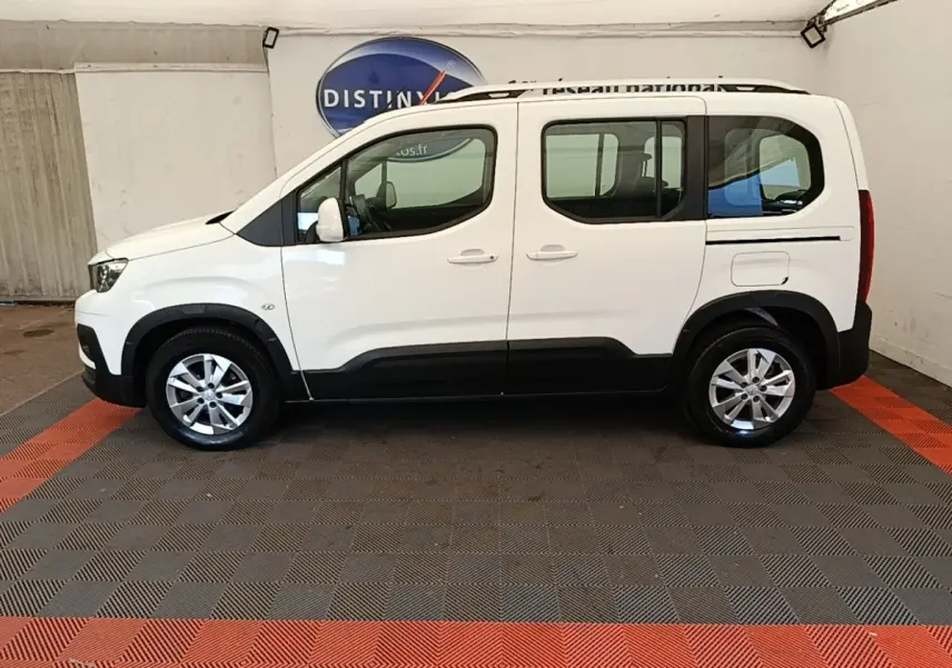 Vue latérale droite d'un Peugeot Rifter blanc 2020 avec barres de toit chromées et jantes alliage.
