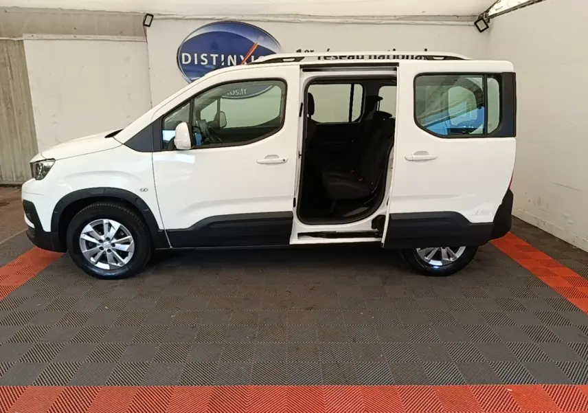 Vue de profil côté gauche d'un Peugeot Rifter blanc 2020 avec porte coulissante arrière ouverte, intérieur visible.