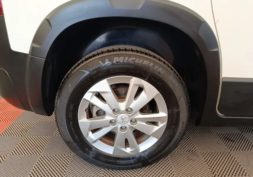 Gros plan sur la roue avant droite du Peugeot Rifter blanc, avec jante alliage et pneu Michelin visible.