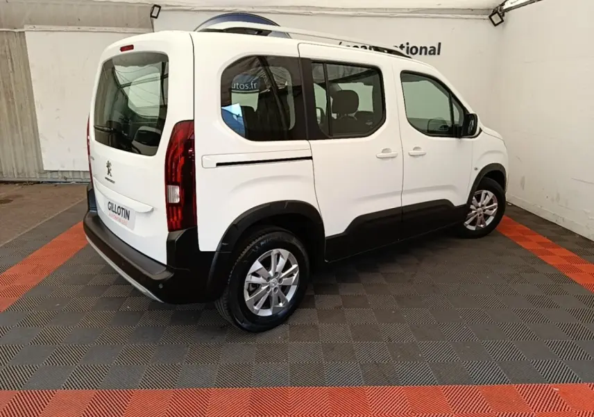 Vue 3/4 arrière droite d’un Peugeot Rifter blanc 2020 avec vitres teintées et jantes alliage.