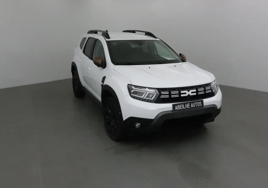 Dacia Duster 4x4 blanc vu en 3/4 avant droit avec rétroviseurs bronze et jantes noires.