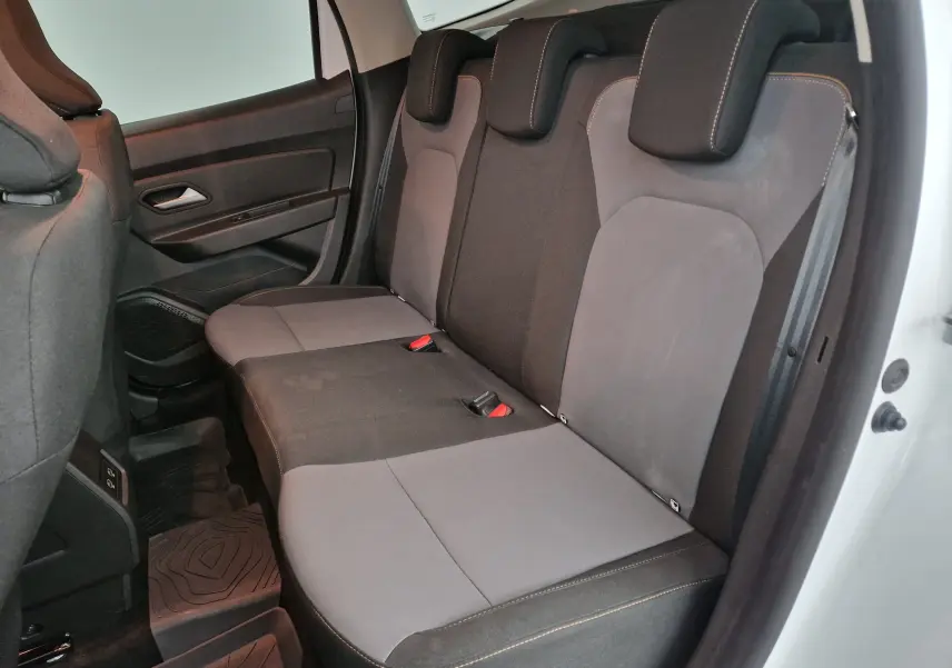 Vue intérieure côté droit des sièges arrière gris et noirs du Dacia Duster 4x4 blanc 2024 avec appuie-têtes ajustables.
