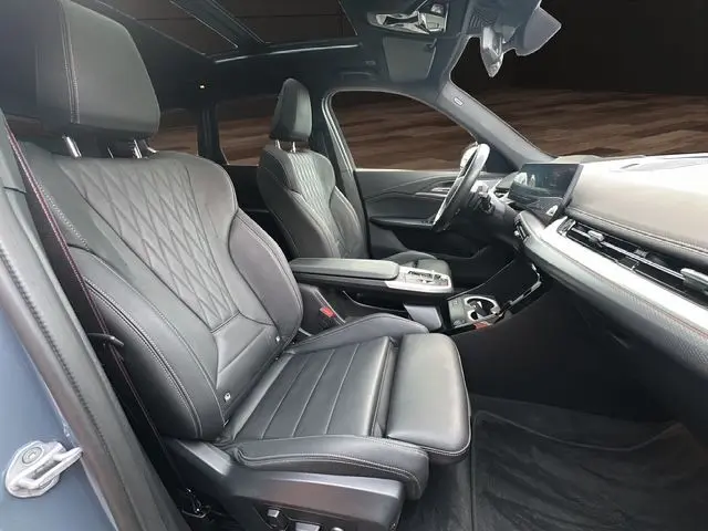 Intérieur BMW X1 XDRIVE 23D 2024 en cuir noir Vernasca, vue côté conducteur avec toit panoramique et tableau de bord moderne.