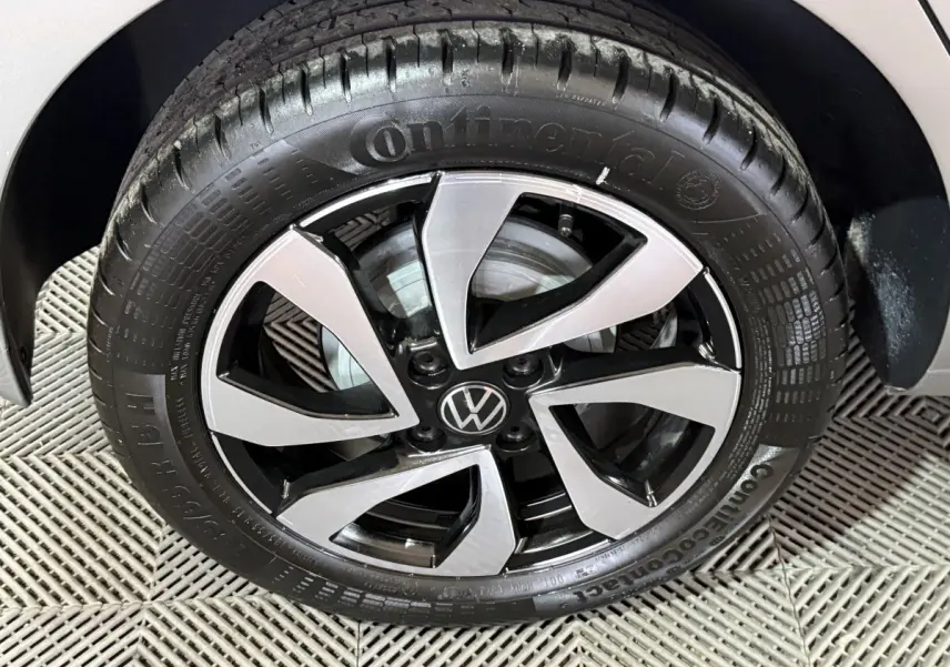 Gros plan sur la roue avant droite d'une Volkswagen Up gris foncé avec jante alliage bicolore et logo VW central.