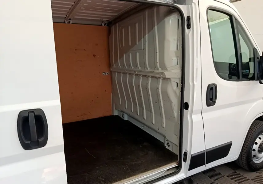 Vue latérale droite d’un fourgon blanc FIAT Ducato 2.3 Multijet 120 avec porte coulissante ouverte montrant l’espace de chargement vide.