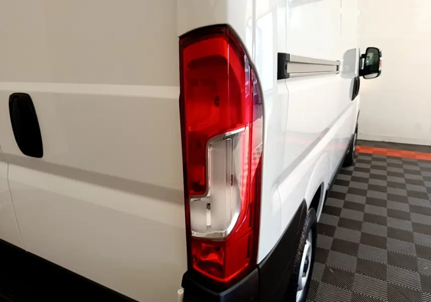 Vue arrière côté droit du FIAT Ducato Fourgon blanc, mettant en valeur le feu arrière et la porte latérale coulissante.