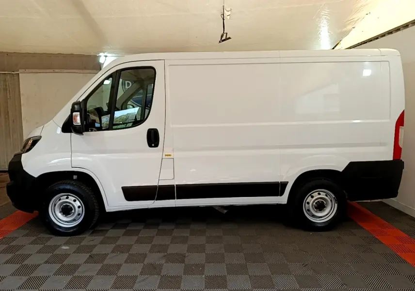 Vue latérale gauche d’un utilitaire blanc FIAT Ducato Fourgon 2021 avec protections noires et jantes acier simples.