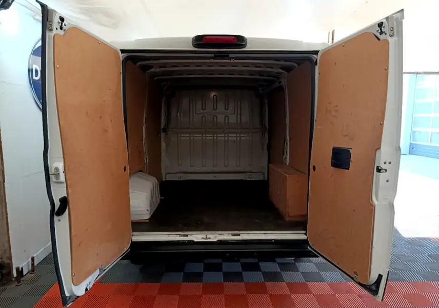 Vue arrière du FIAT Ducato Fourgon blanc 2021 avec portes ouvertes montrant l’espace de chargement vide et habillage bois intérieur.