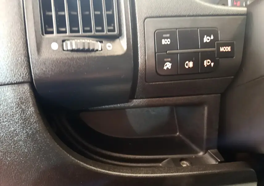 Gros plan sur les commandes d'éclairage et la ventilation côté conducteur du tableau de bord noir du Fiat Ducato Fourgon blanc.