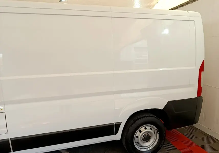 Vue latérale droite d’un fourgon FIAT Ducato blanc 2021 avec jante acier et protections noires sur bas de caisse.