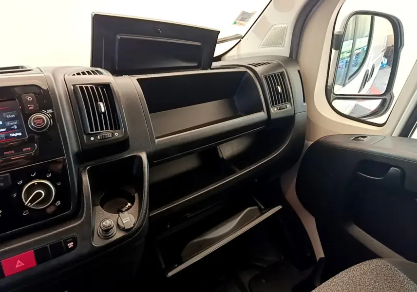 Vue intérieure côté passager du tableau de bord noir et des rangements ouverts du Fiat Ducato Fourgon blanc 2021.