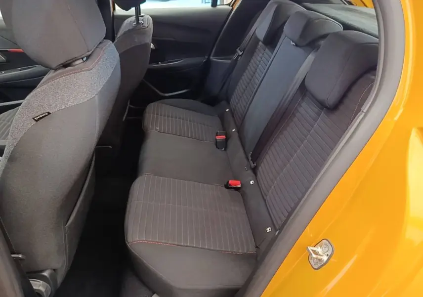 Vue intérieure côté droit sur la banquette arrière noire avec surpiqûres rouges d'une Peugeot 208 jaune 2023.