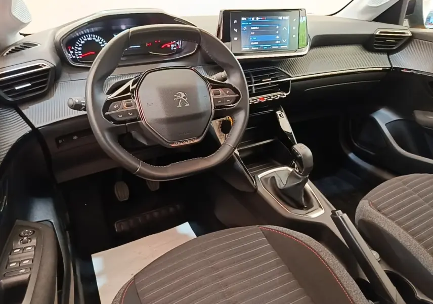 Intérieur de la Peugeot 208 PureTech 75 S&S Active Pack 2023, vue avant centrée sur le volant cuir et la console tactile.