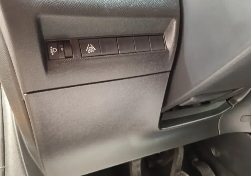 Vue intérieure côté conducteur du tableau de bord bas avec commandes de réglage des phares et d'assistance à la conduite.