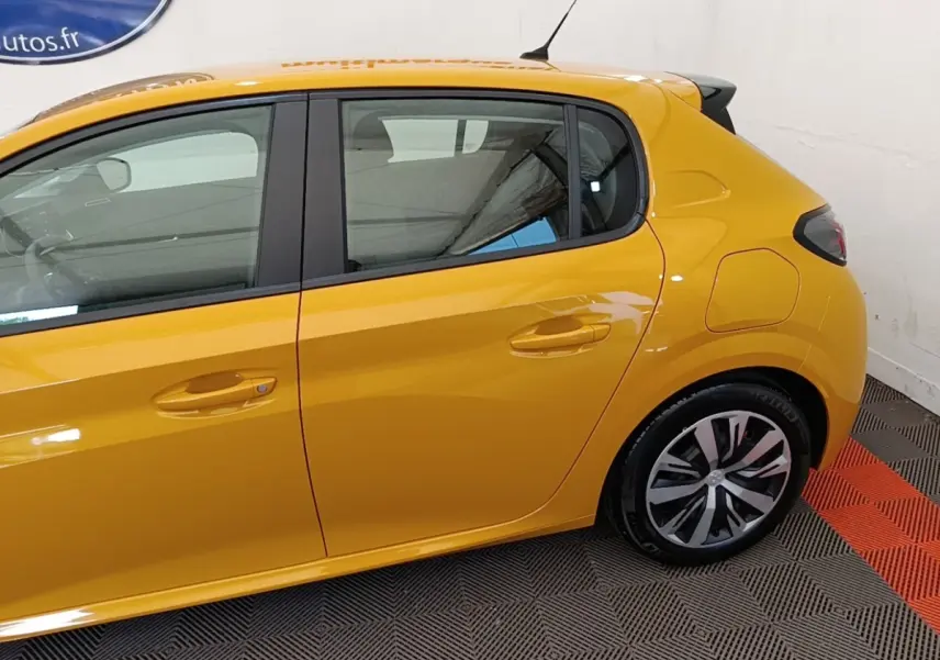 Vue latérale côté gauche d'une Peugeot 208 jaune 2023 avec jantes alliage et poignées de porte ton caisse.