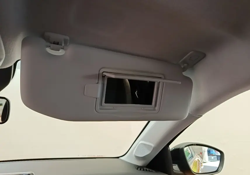 Détail de pare-soleil avec miroir intégré côté conducteur dans l'habitacle d'une Peugeot 208 jaune 2023.