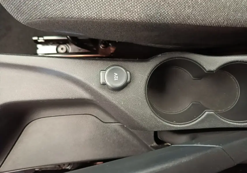 Vue rapprochée de la console centrale noire de la Peugeot 208 avec prise 12V et porte-gobelets.