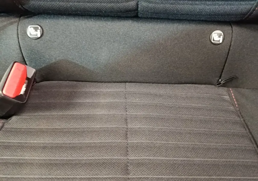 Gros plan sur la banquette arrière noire de la Peugeot 208, avec boucle de ceinture rouge et fixations Isofix visibles.