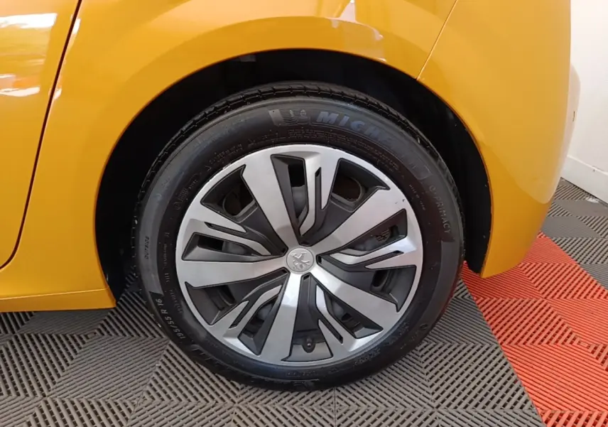 Gros plan sur la roue arrière droite d'une Peugeot 208 jaune 2023 avec jante alliage et pneu Michelin.