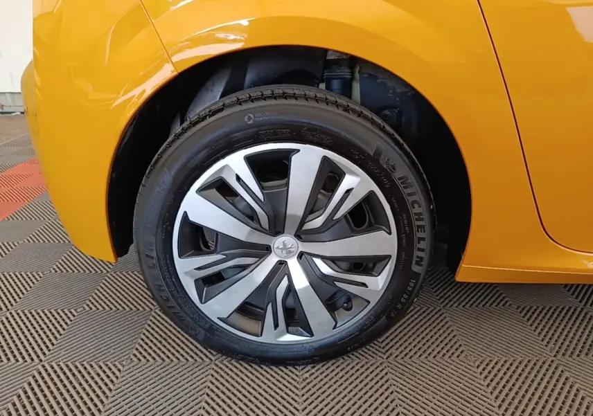 Gros plan sur la roue avant droite d'une Peugeot 208 jaune 2023 avec jante alliage et pneu Michelin.
