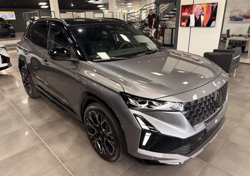 Renault Austral full hybrid gris schiste toit noir, vue 3/4 avant avec calandre noire et jantes noires en showroom.