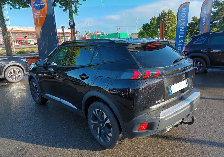 Peugeot 2008 noir en 3/4 arrière droit, avec feux arrière à motifs griffes et attelage visible sous le pare-chocs.