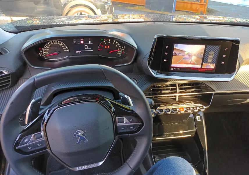 Vue intérieure du tableau de bord et volant noir du Peugeot 2008 PureTech 130 Allure 2022 avec écran tactile affichant la caméra de recul.