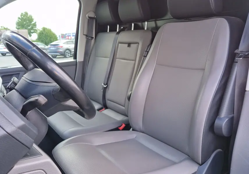 Vue intérieure côté conducteur du Volkswagen Transporter 2.0 TDi 2020 avec sièges gris et volant multifonction noir.