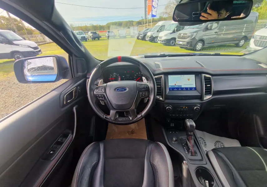Vue intérieure du Ford Ranger Raptor 2022 montrant le volant sport avec marquage rouge et écran tactile central.