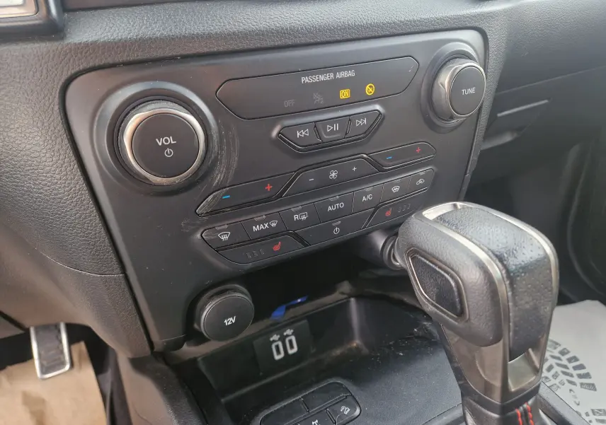 Vue rapprochée du tableau de bord et levier de vitesse du Ford Ranger Raptor 2022, finition noire avec commandes climatisation et audio.