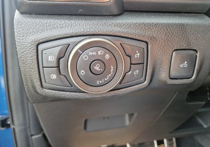 Gros plan sur le bouton de commande des phares et éclairages du Ford Ranger Raptor bleu, côté gauche du tableau de bord.