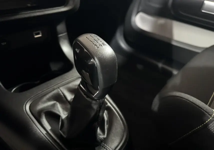Le levier de vitesses manuel noir de la Citroën C3 PureTech 82 vu en gros plan côté conducteur.
