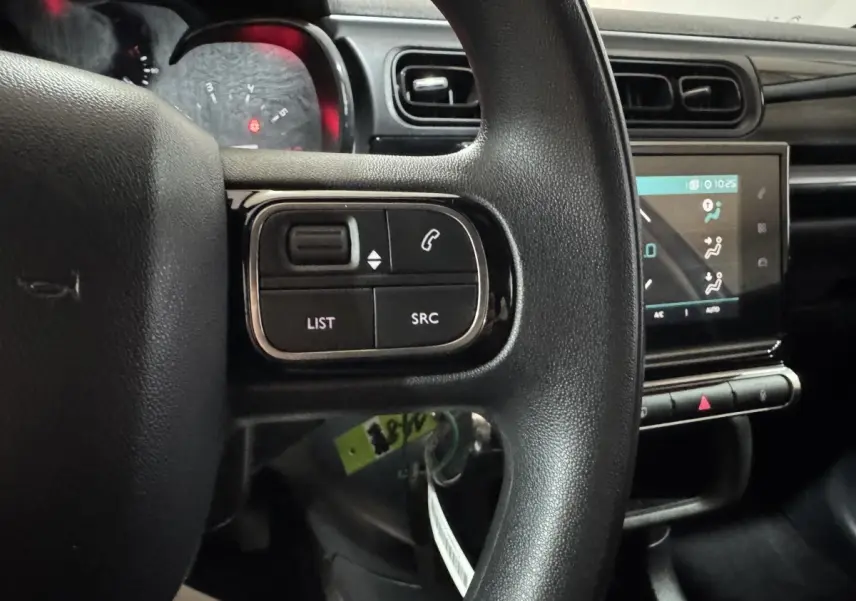 Gros plan sur le volant noir et l'écran tactile central du tableau de bord de la Citroën C3 bleu 2018.