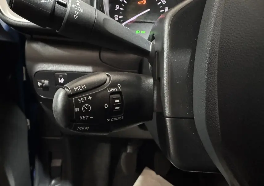 Gros plan sur la commande de régulateur de vitesse à gauche du volant d'une Citroën C3 bleu 2018.