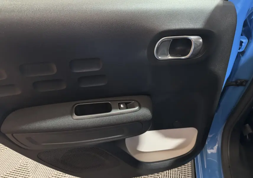 Gros plan sur la porte avant gauche bleu clair d'une Citroën C3 2018 avec poignée argentée et bouton de verrouillage.