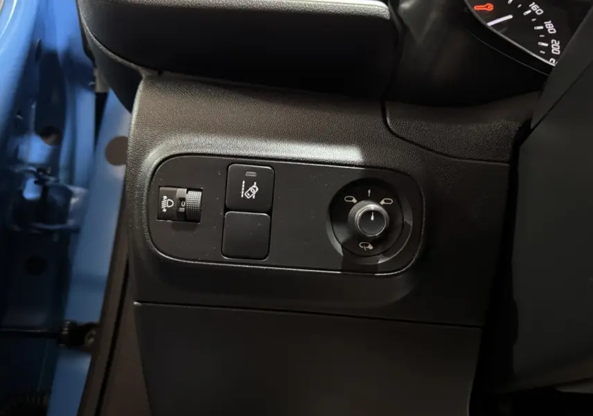 Gros plan sur les commandes côté gauche d'une Citroën C3 bleu 2018, avec réglage phares et rétroviseurs.
