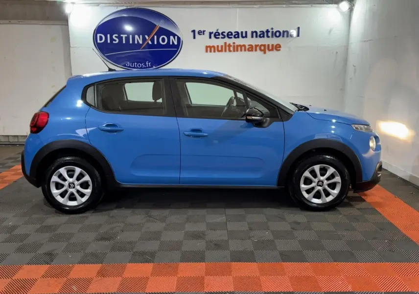 Profil côté gauche d'une Citroën C3 bleu 2018 dans un showroom avec sol à damier noir et orange.