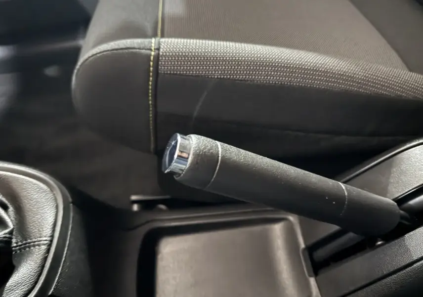 Gros plan sur le frein à main en cuir noir et la console centrale d'une Citroën C3 2018, intérieur sombre.