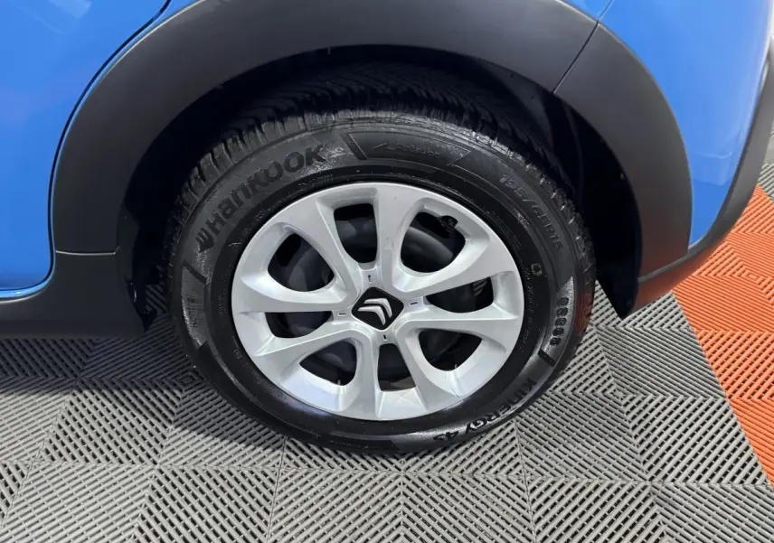 Gros plan sur la roue avant droite d'une Citroën C3 bleu 2018 avec jante argentée et logo Citroën central.