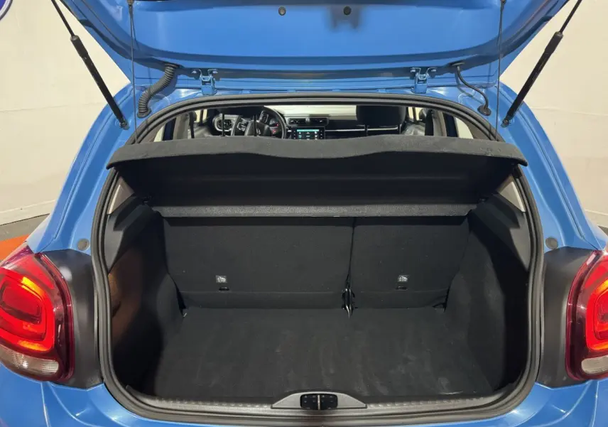 Coffre ouvert d'une Citroën C3 bleu 2018, vue arrière montrant l'intérieur spacieux et la tablette de séparation.
