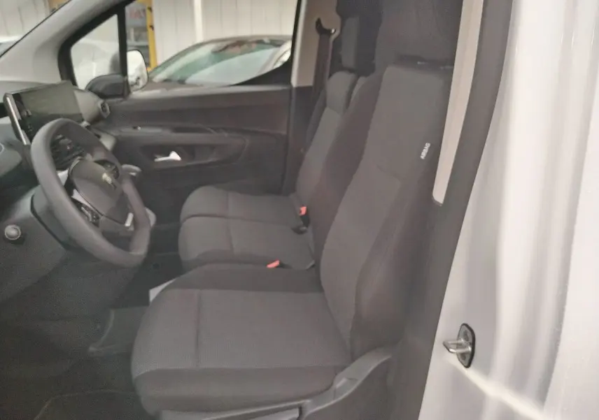 Vue intérieure côté conducteur du Peugeot Partner Fourgon blanc Icy 2025, montrant les sièges avant et le volant.